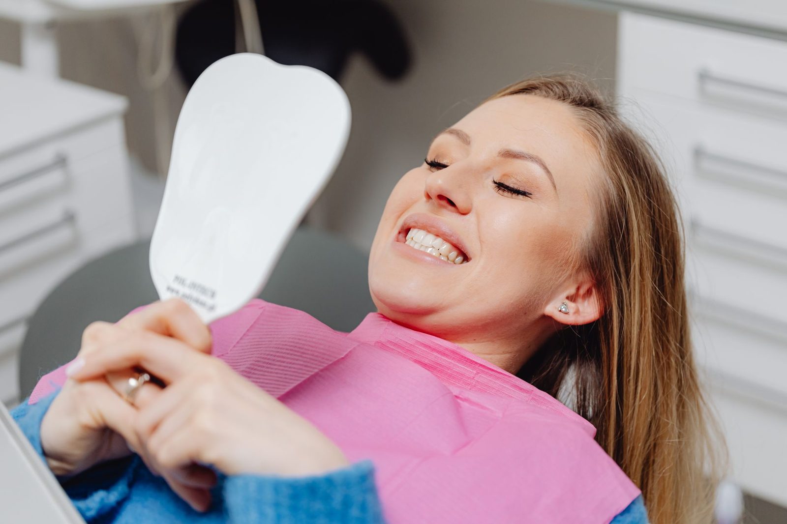 Woman smiling at her new teeth in a mirror